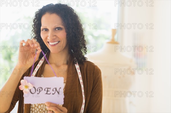 Portrait of woman holding open sign.