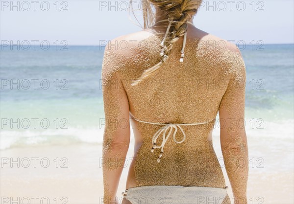 Woman's back with sticking sand . Photo : Jamie Grill