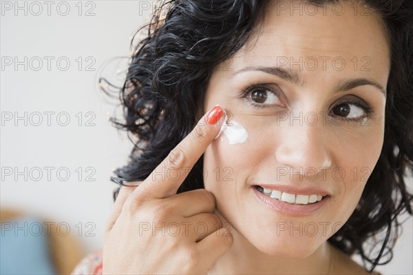 Mature woman applying anti-ageing cream. Photo : Jamie Grill