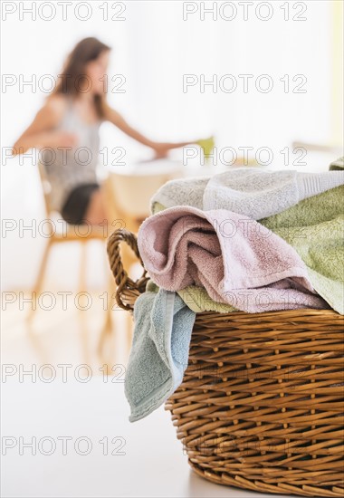 Woman in kitchen with laundry basket in foreground. Photo : Daniel Grill