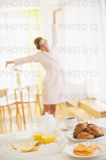 Breakfast scene with woman in white robe stretching. Photo : Daniel Grill