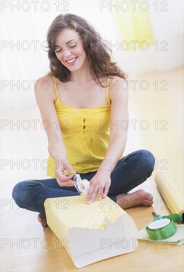 Young woman packing presents. Photo : Daniel Grill