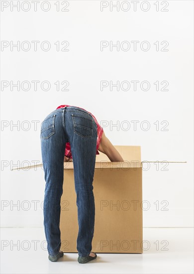 Studio shot of young woman looking into box. Photo : Daniel Grill