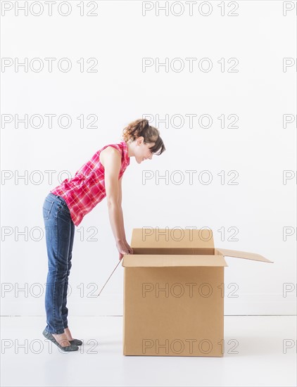 Studio shot of young woman looking into box. Photo : Daniel Grill