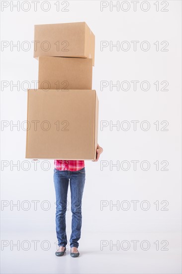 Studio shot of young woman carrying stack of boxes. Photo: Daniel Grill