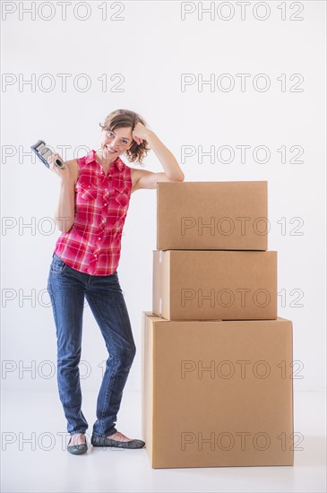 Studio shot of young woman with tape and stack of boxes. Photo : Daniel Grill