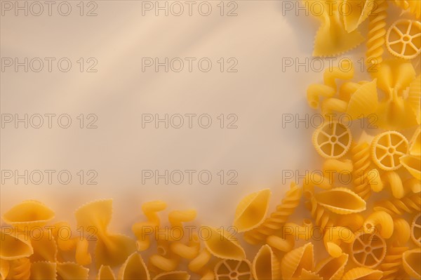 Variety of yellow pasta with blank white space in upper left corner. Photo : Daniel Grill