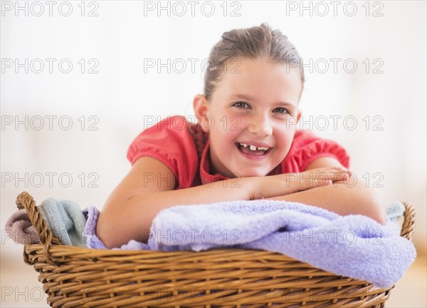 Young girl (8-9) leaning on laundry basket. Photo: Daniel Grill