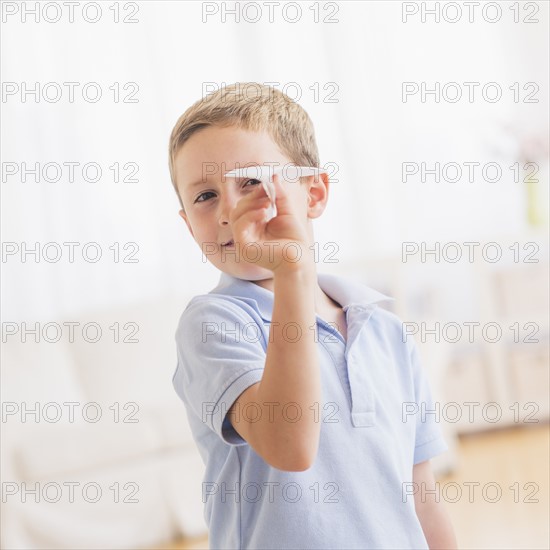 Young boy (6-7) playing with paper plane. Photo : Daniel Grill