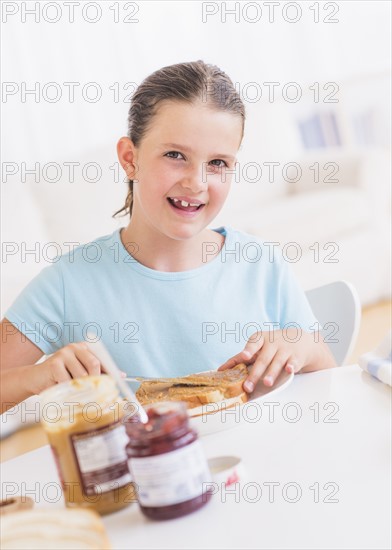 Happy young girl (8-9) having breakfast. Photo : Daniel Grill