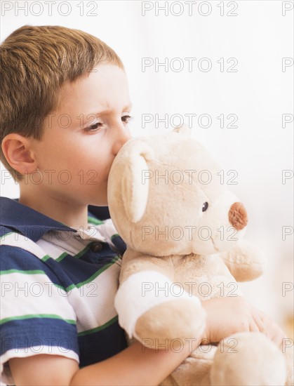 Boy (6-7) hugging his teddy-bear. Photo : Daniel Grill