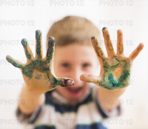 Young boy (6-7) showing hands stained with paint. Photo : Daniel Grill