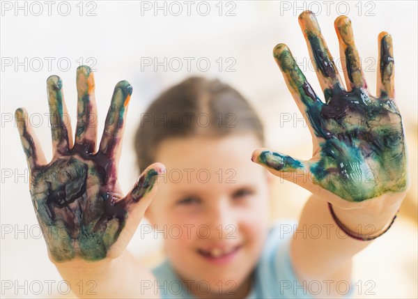 Young girl (8-9) showing hands stained with paint. Photo : Daniel Grill