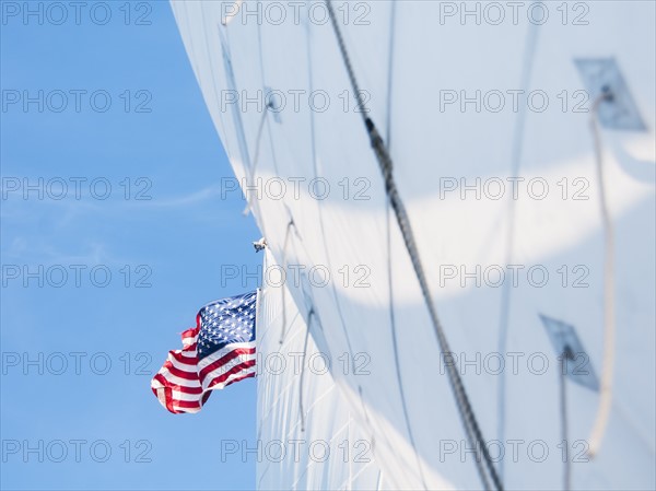 White sails and American flag against blue sky. Photo: Daniel Grill