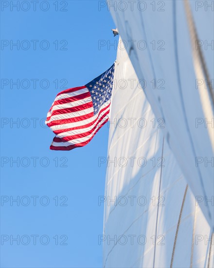 White sails and American flag against blue sky. Photo: Daniel Grill