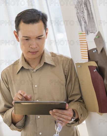 Mid adult fashion designer using digital tablet. Photo : Daniel Grill