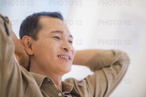 Profile of happy mid adult man with hands behind his back. Photo : Daniel Grill