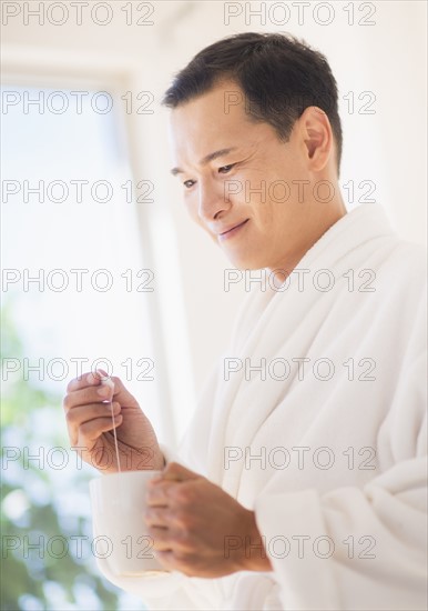 Mid adult man mixing herbal tea. Photo : Daniel Grill