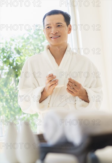 Mid adult man holding cup of healthy herbal tea. Photo : Daniel Grill