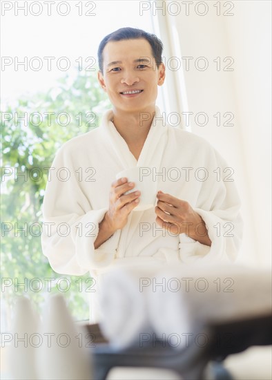 Mid adult man holding cup of healthy herbal tea. Photo: Daniel Grill
