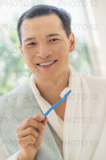 Happy mid adult man holding toothbrush. Photo: Daniel Grill