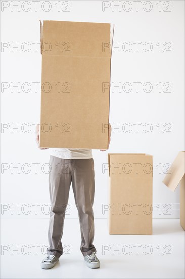 Mid adult man hiding inside of cardboard box. Photo : Daniel Grill