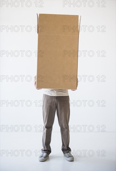 Mid adult man hiding inside of cardboard box. Photo : Daniel Grill