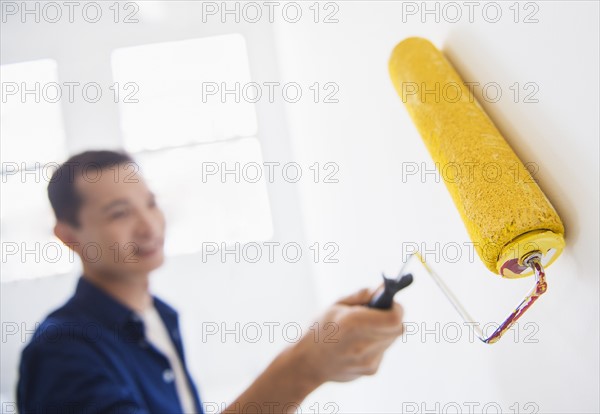 Man painting wall with painting roll. Photo : Daniel Grill