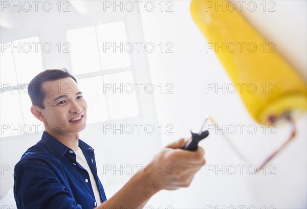 Man painting wall with painting roll. Photo: Daniel Grill