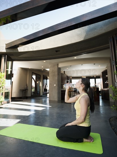 Young attractive woman taking a break in practicing yoga to drink some water.