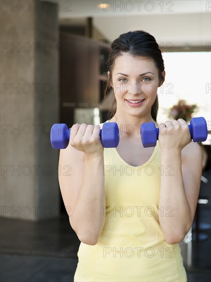 Young attractive woman exercising with dumbbells.