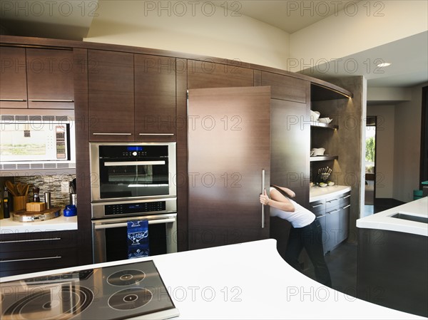 Young woman bustling around in modern domestic kitchen.