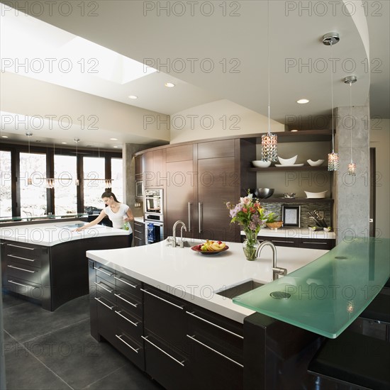 Young woman bustling around in modern domestic kitchen.