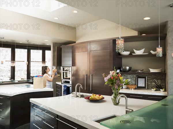 Young woman bustling around in modern domestic kitchen. Photo: Erik Isakson