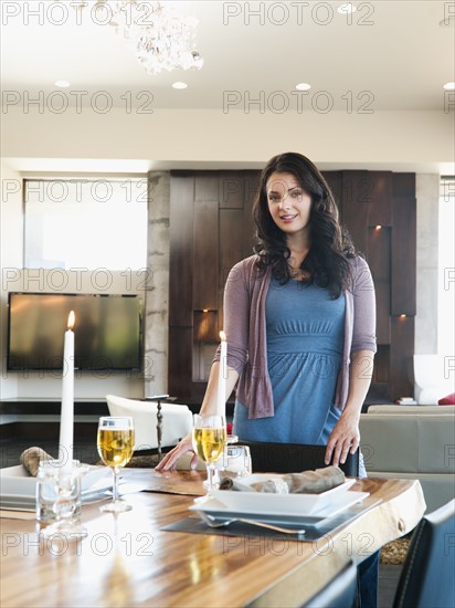 Young attractive woman standing behind table prepared for dinner. Photo: Erik Isakson