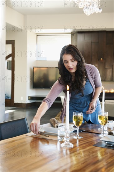 Young attractive woman preparing table for dinner.