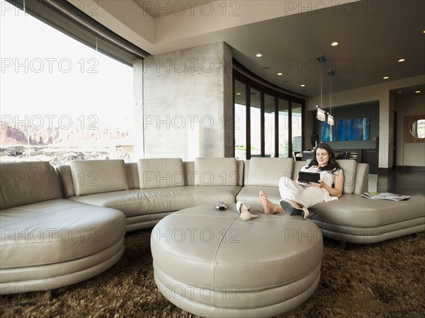 Young attractive woman using digital tablet while sitting in her living room.