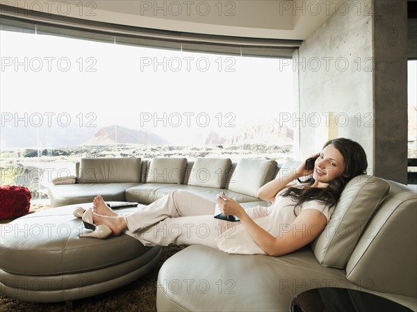 Young attractive woman using mobile phone while sitting in her living room. Photo: Erik Isakson