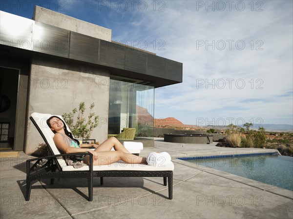 Young attractive woman sunbathing by swimming pool.