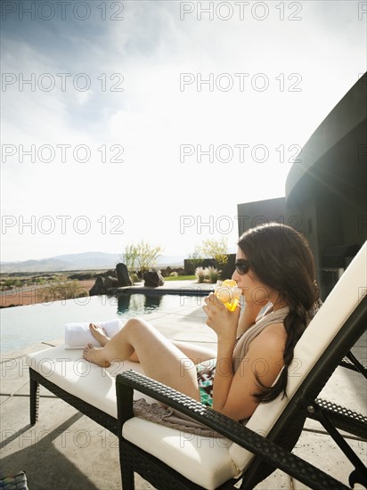 Young attractive woman enjoying cocktail by swimming pool.