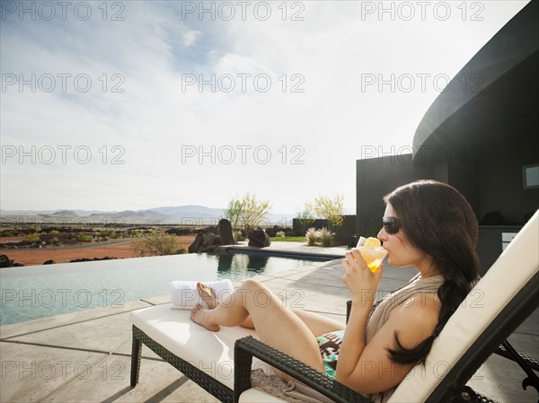 Young attractive woman enjoying cocktail by swimming pool.