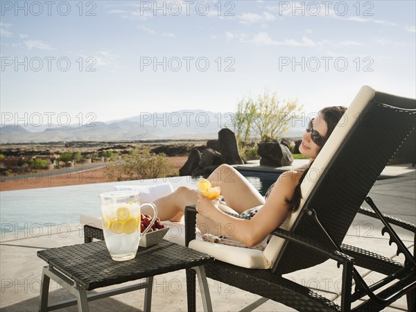 Young attractive woman enjoying cocktail by swimming pool.