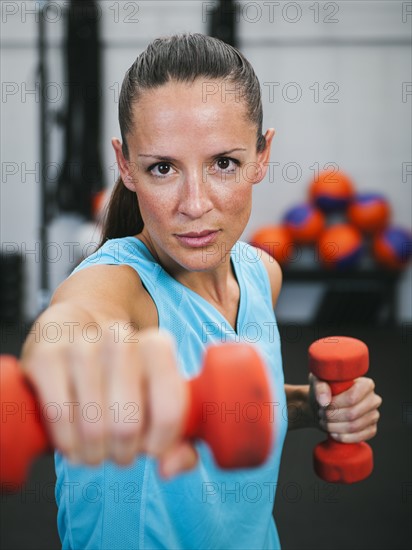 Mid adult woman exercising with dumbbells.