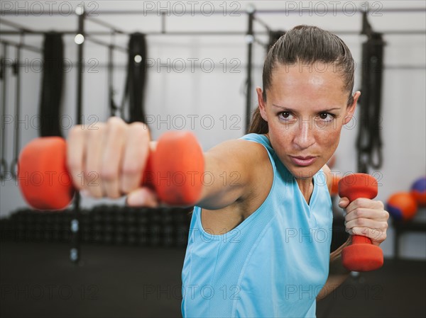 Mid adult woman exercising with dumbbells.