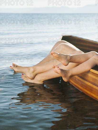 Feet of boy (4-5) and two adult people sticking out of boat.