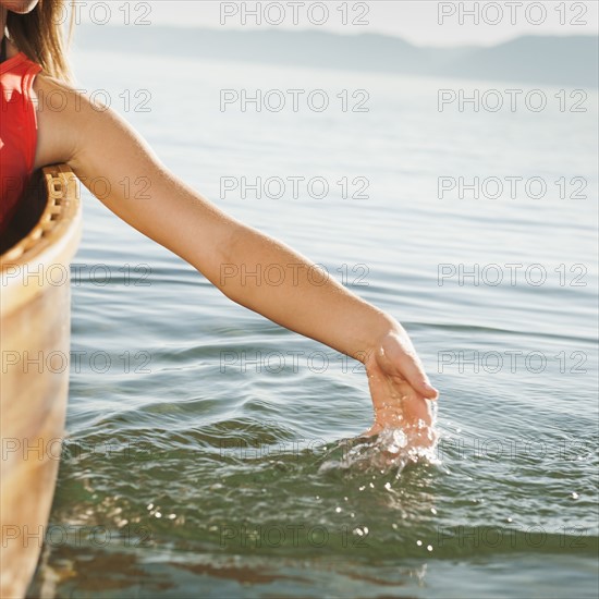 Young woman's hand splashing lake water.