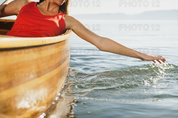 Young woman's hand splashing lake water.