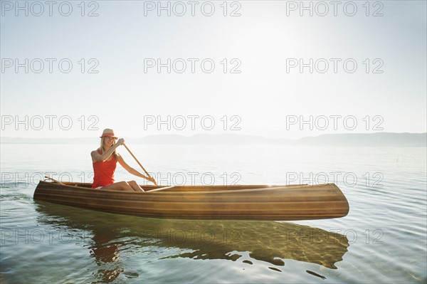 Portrait of young woman paddling canoe.