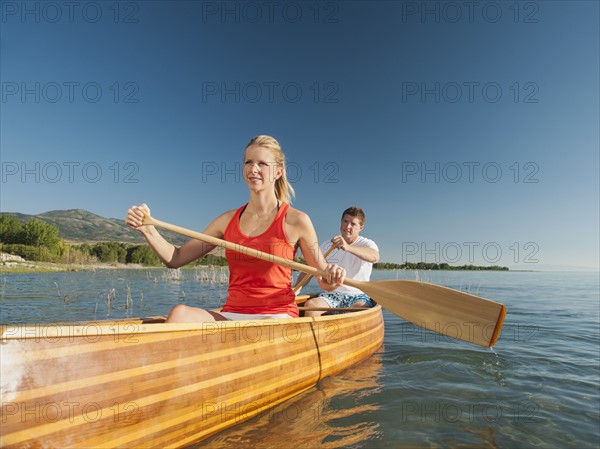 Portrait of two young people paddling canoe.