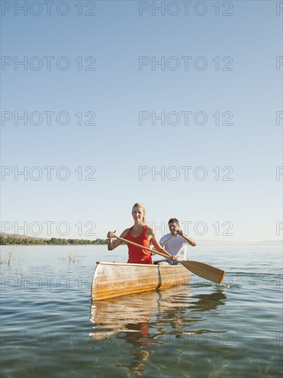 Portrait of two young people paddling canoe.